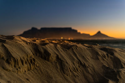 Scenic view of beach and table mountain against sky during sunset