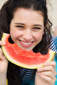 Happy woman eating watermelon at beach