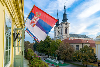 Low angle view of flag amidst buildings in city against sky