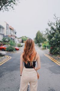 Rear view of woman with umbrella standing on road