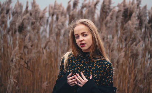 Portrait of beautiful young woman against plants