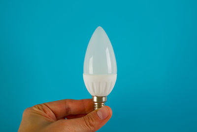 Close-up of hand holding ice cream against blue background