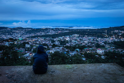 Young girl watching downtown city view with dramatic cloudy sky at evening from mountain top