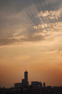 Silhouette of buildings against cloudy sky during sunset