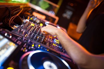 Close-up of man playing on sound mixer at nightclub