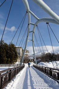 People walking on footbridge in city during winter