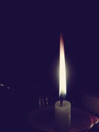 Close-up of lit candle in dark room