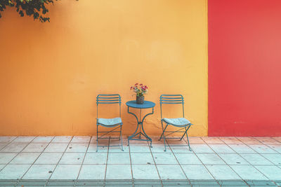 Blue empty chairs  and table against  orange wall