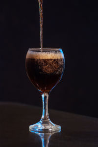 Close-up of wineglass on table against black background