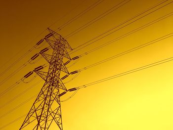 Low angle view of silhouette electricity pylon against sky during sunset