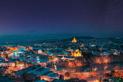 High angle view of illuminated buildings in city against sky at night