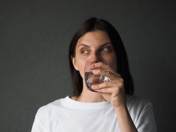 Portrait of young woman drinking water at home