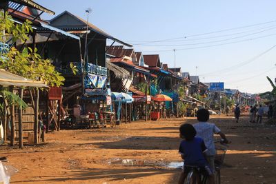 Rear view of people walking on road against buildings