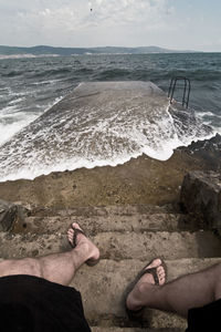 Low section of man sitting on steps at beach
