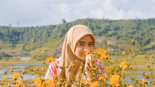 Portrait of woman with flowers in field