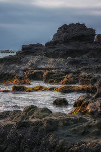 Rock formations by sea against sky