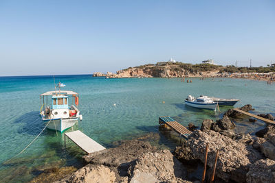 Sailboats moored on sea against clear sky