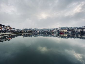 Reflection of buildings on river against sky in city