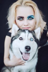 Portrait of young fashion model with siberian husky against black background