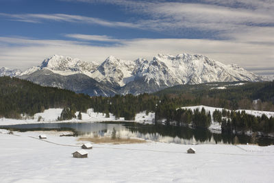 Scenic view of lake by snowcapped mountains against sky