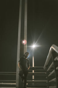 Young man standing on bridge at night