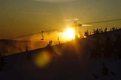 Silhouette of ski lift during sunset