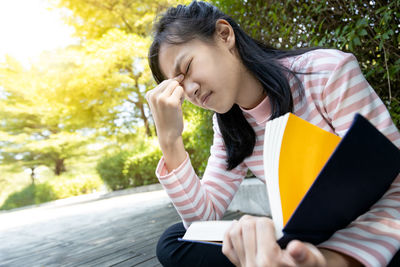 Young woman looking away while sitting on book