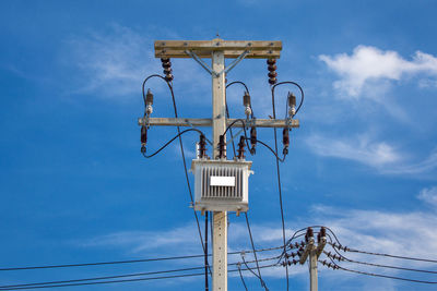 Low angle view of electricity pylon against blue sky