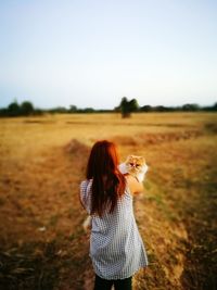 Woman with cat standing on field against sky