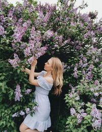 Beautiful woman standing by pink flowering plant