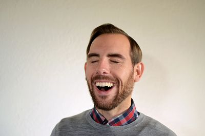 Close-up of man laughing against wall