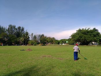 Rear view of man standing on golf course against sky