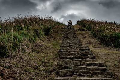 Woman taking video with gimbal at top of the steps on keelung mountain, taipei, taiwan.