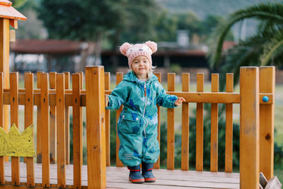 Full length of young woman standing against fence