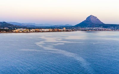 Scenic view of sea and mountains against clear sky during sunset