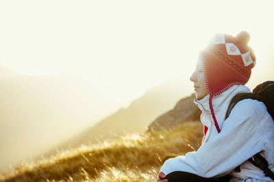 Side view of young woman on field against clear sky