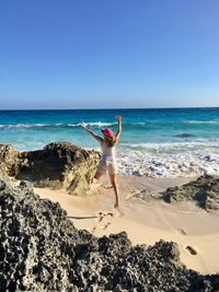 Full length of woman jumping on shore at beach