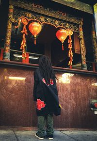 Rear view of woman standing against illuminated building