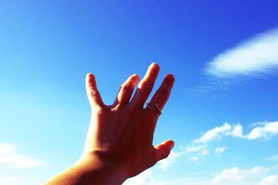Low angle view of human hand against sky