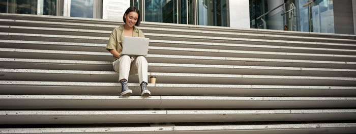 Full length of young woman standing on steps