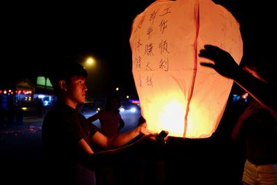 People holding illuminated lantern at night