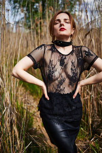 Young woman standing against plants