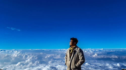 Man looking away against blue sky