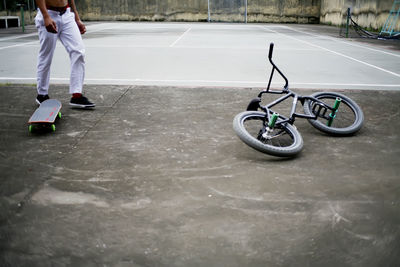 Low section of man walking by bicycle and skateboard