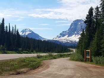 Road by trees and mountains against sky