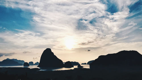 Silhouette rocks by sea against sky during sunset