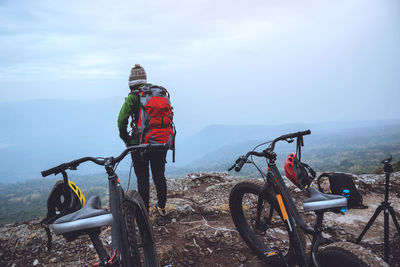 Rear view of woman with backpack standing on mountain during foggy weather