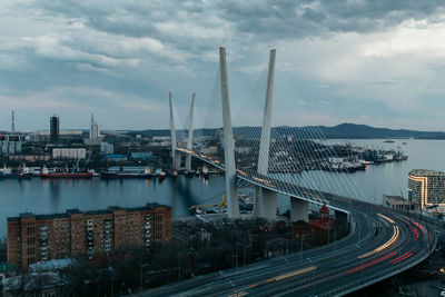 Aerial view of city at waterfront against cloudy sky