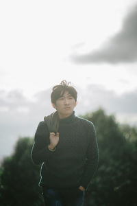 Portrait of young man standing against sky