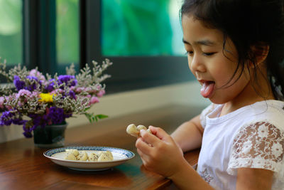 Close-up of smiling girl with ice cream in plate on table